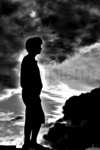 Gegenlicht - Ein Jugendlicher steht auf einem Betonpodest und schaut in die Ferne.